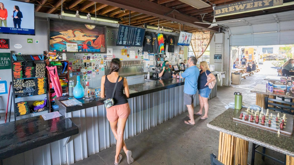 A couple of people at the bar, with open garage door leading to outdoor space.