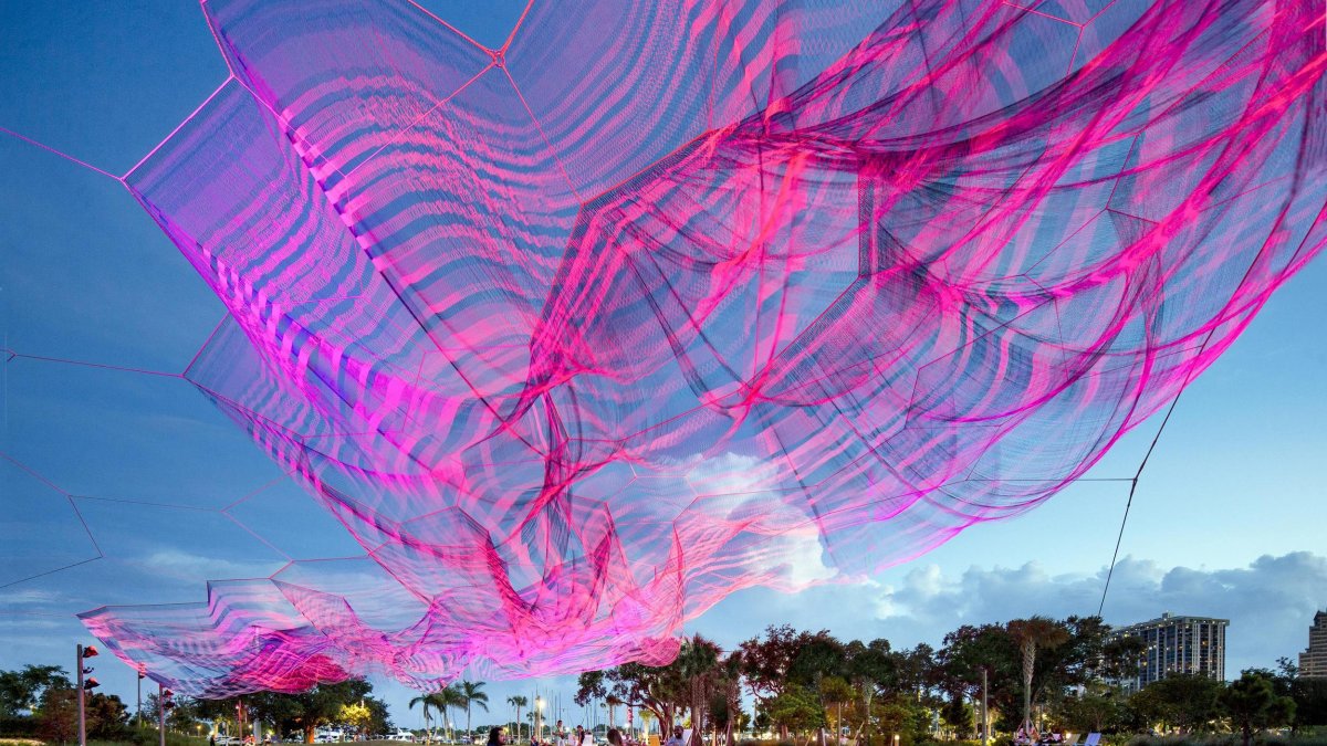 a free flowing magenta sculpture by Janet Echelman on the lawn near the St. Pete Pier