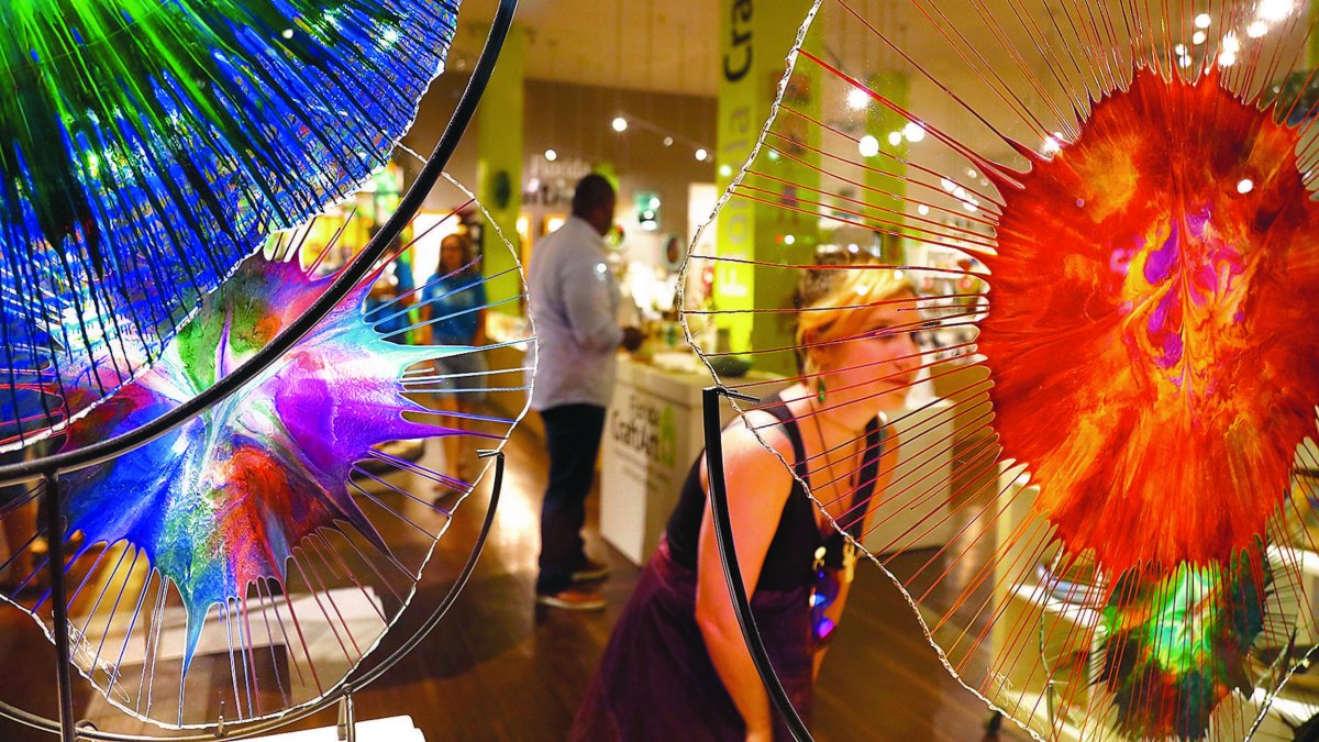 Woman shopping surrounded by colorful glass sculptures.