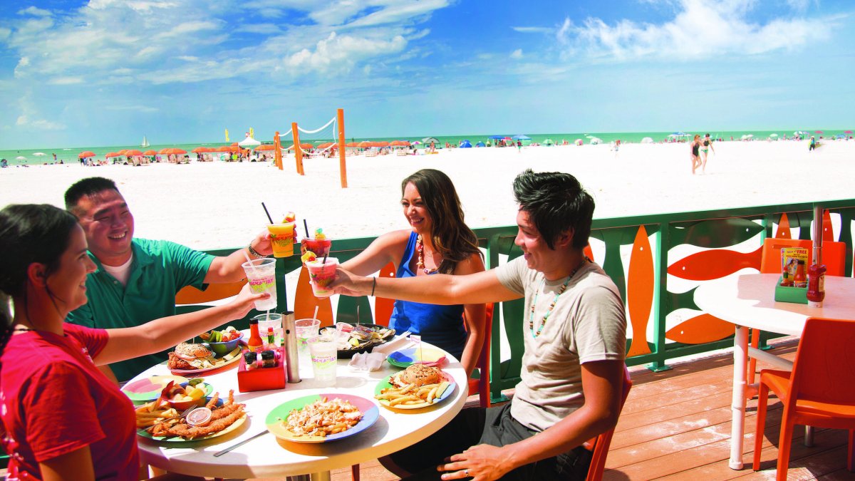 Family toasting at open-air table overlooking the beach