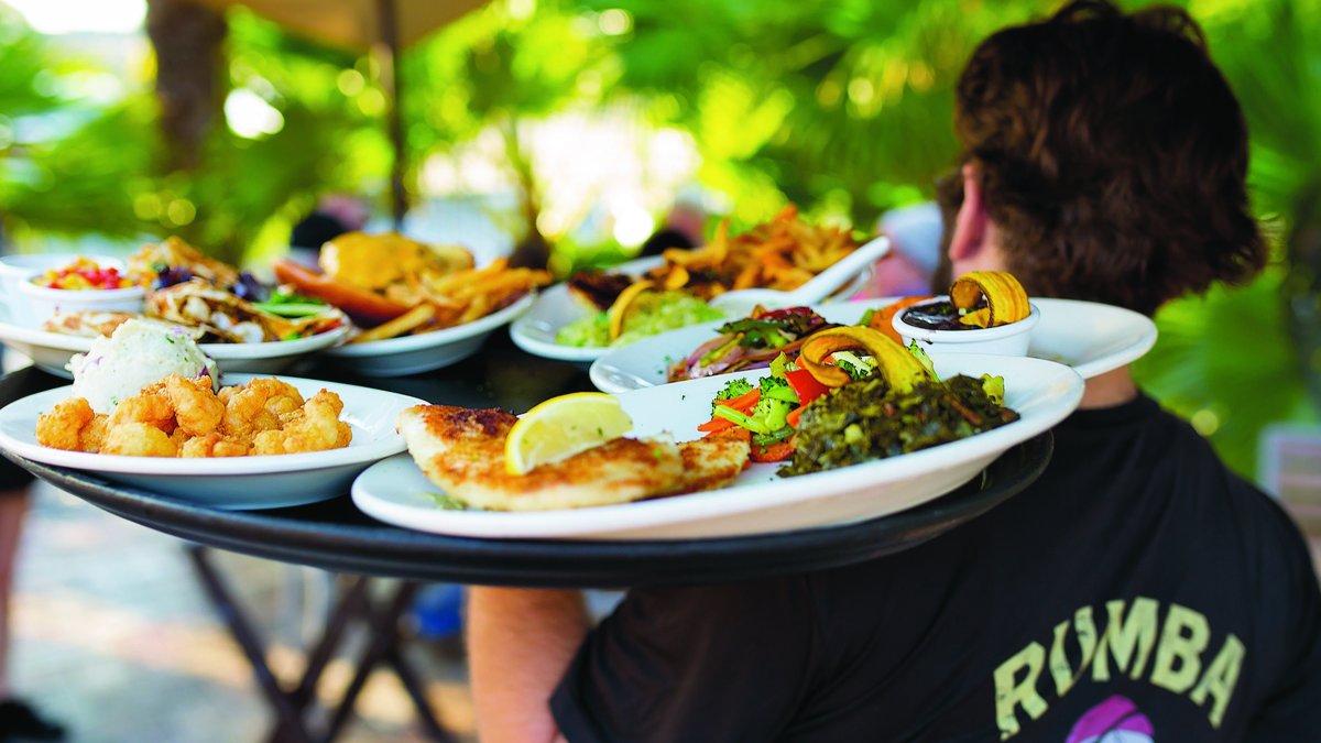 Waiter carries tray of seafood and other dishes