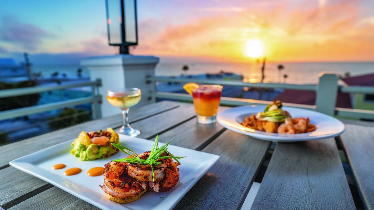 Plates of seafood on a table overlooking a beach sunset