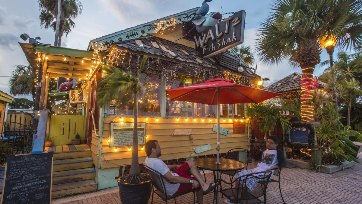 Exterior of a small, funky fish shack with one table out front