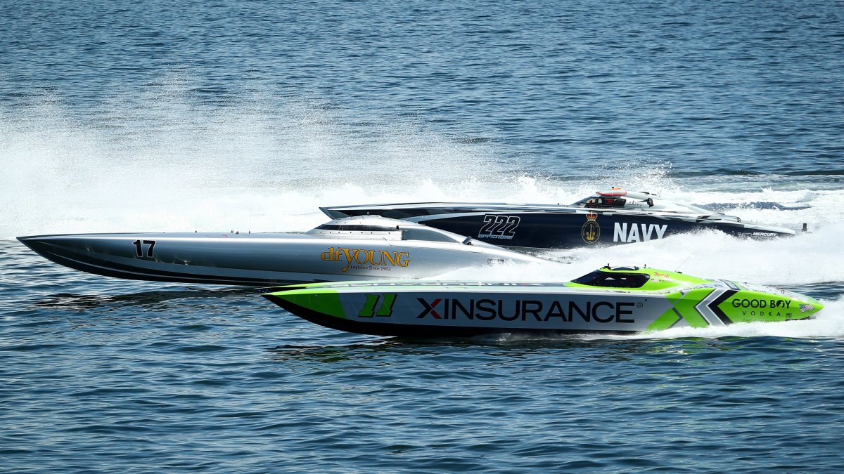 Two powerboats racing next to one another on the water during the day.