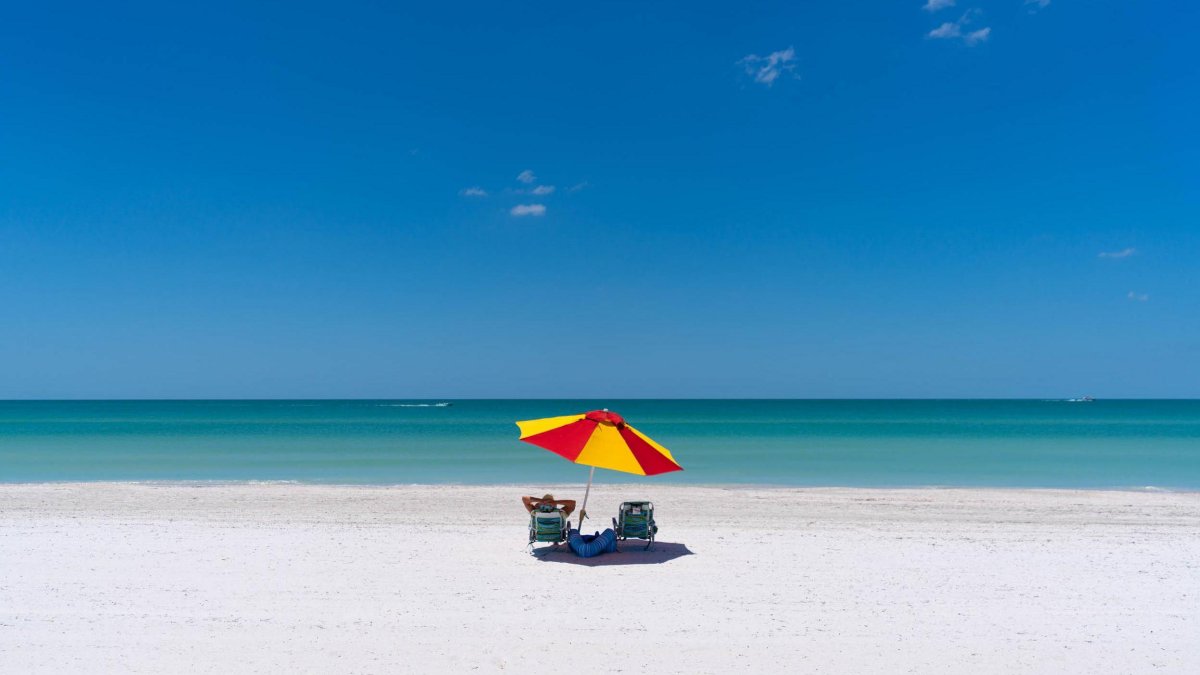 Guarda-sol vermelho e amarelo na linda praia vazia