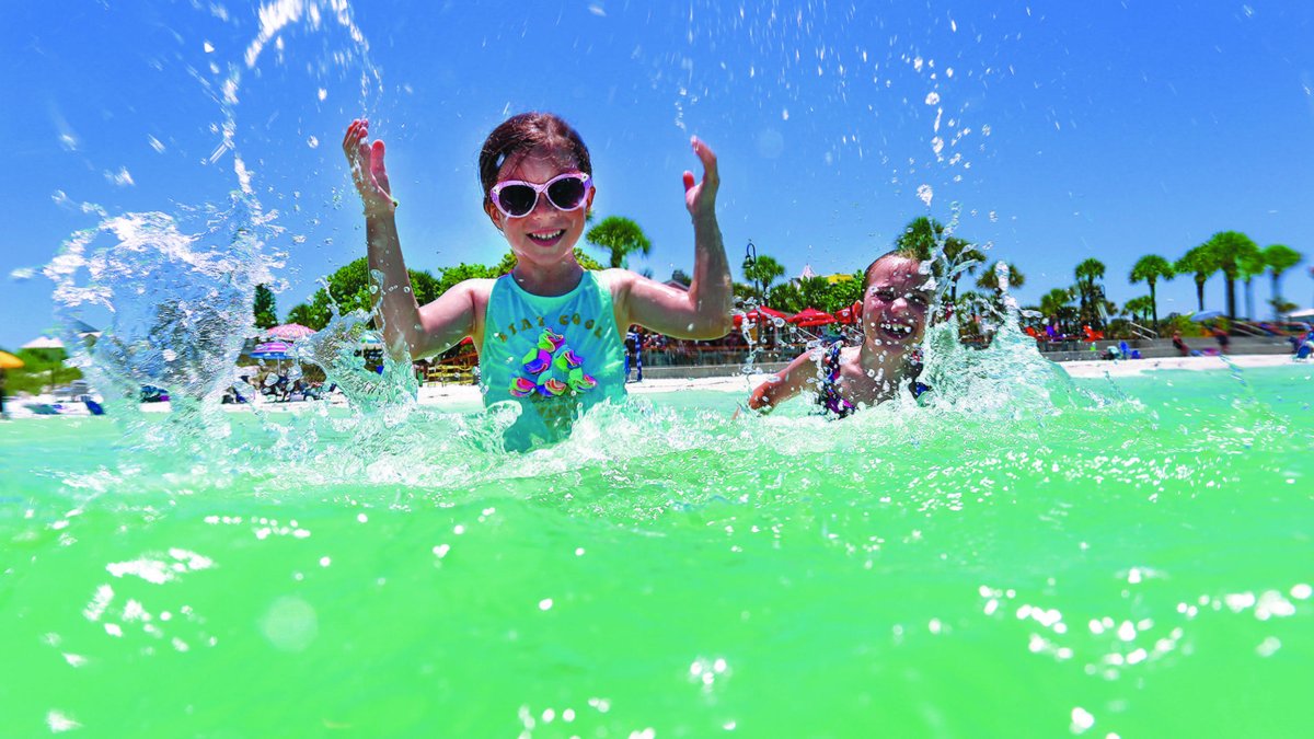 Kids in water wearing swim goggles splash while playing