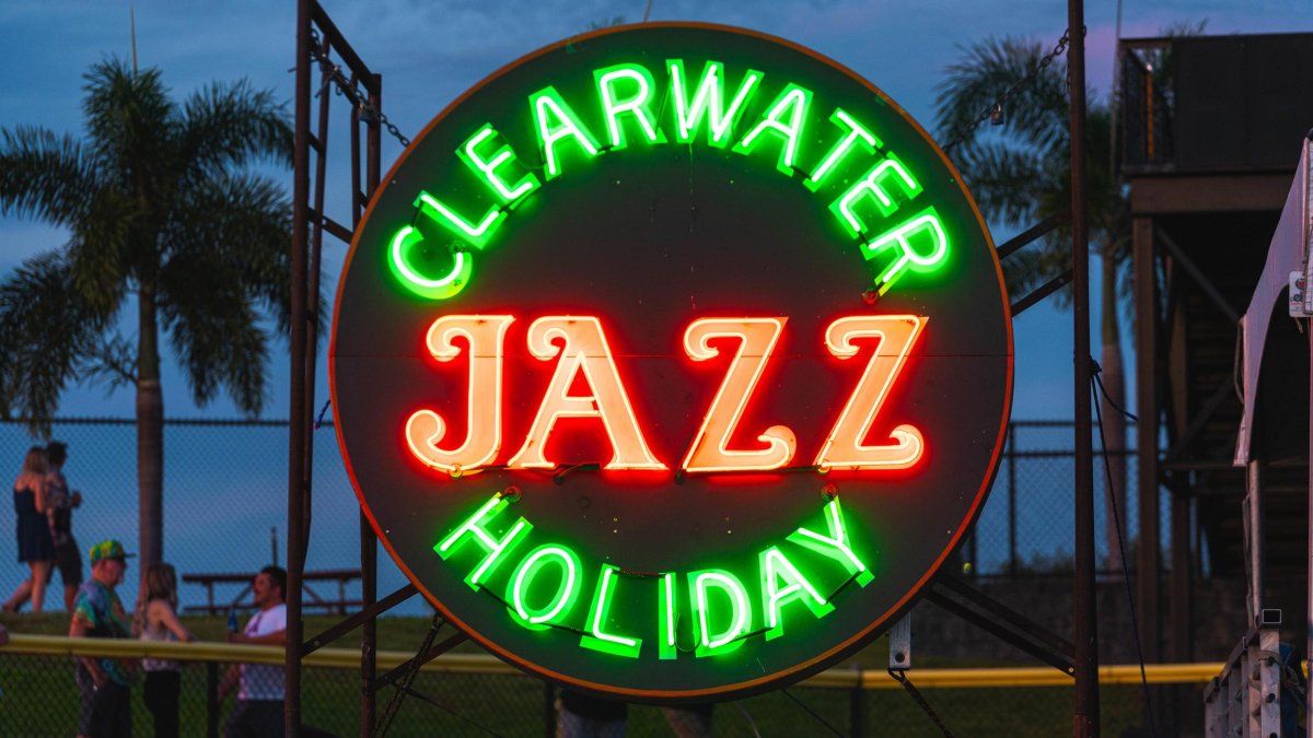 A lit neon Clearwater Jazz Holiday sign at dusk.