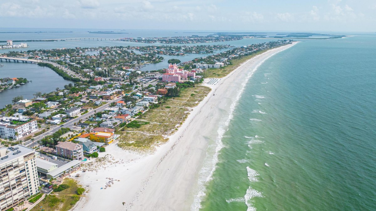 aerial view of st pete beach with buildings on left and white beach green water