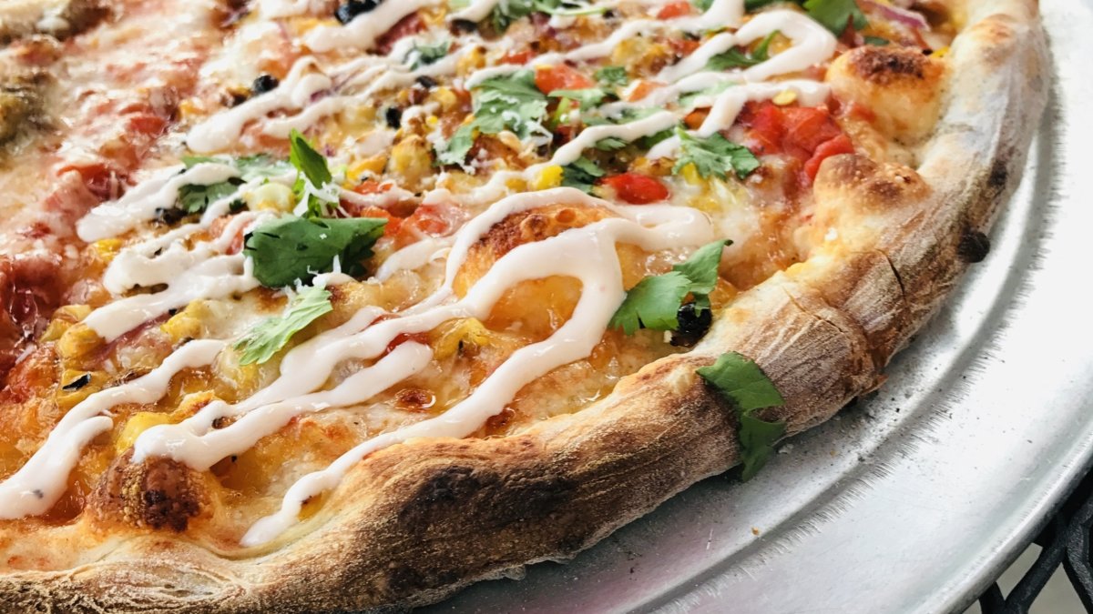 Close-up of a pizza with fresh basil and a creamy sauce drizzled on top