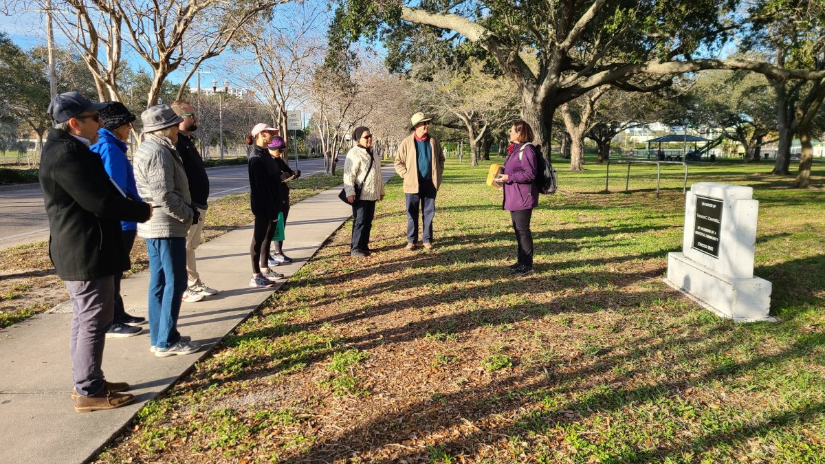 a group of people gathers around a speaker on a walking tour