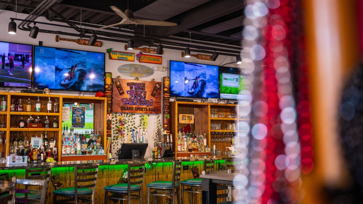 a colorful bar area with multiple TVS and green bar stools