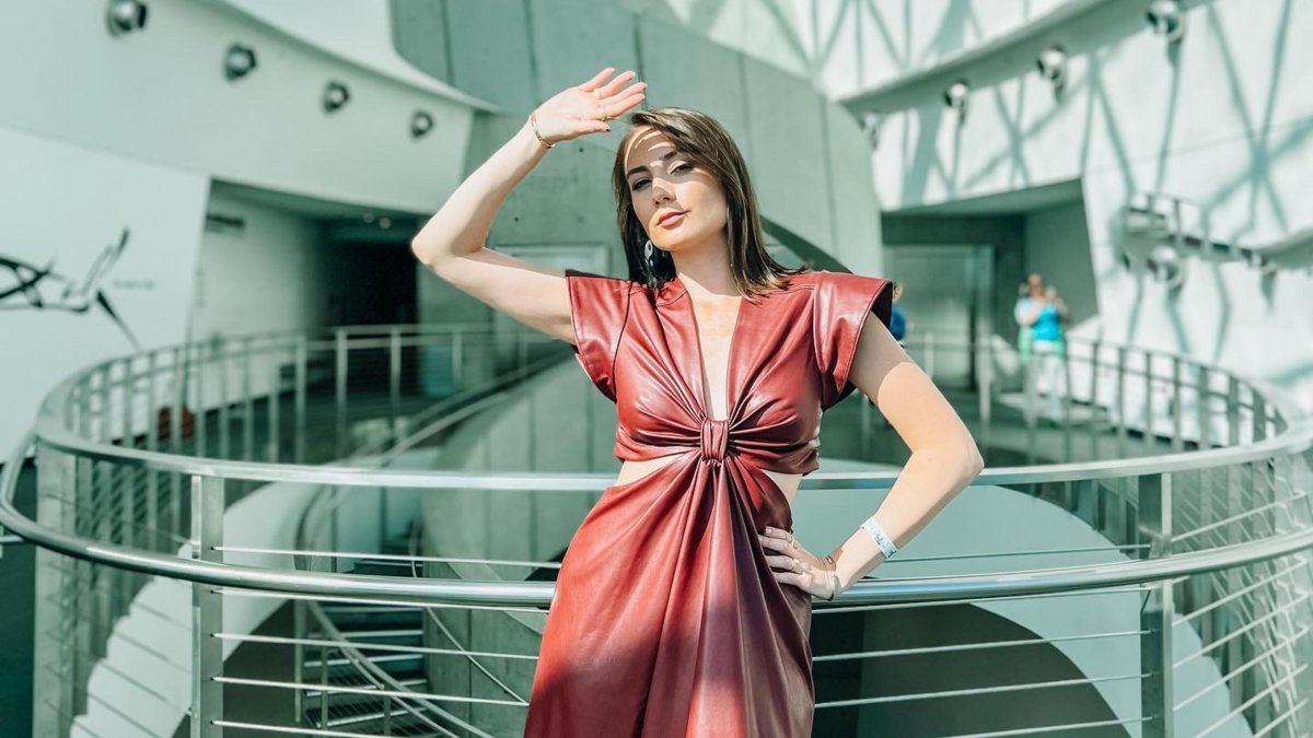 a glamorous woman in a rust-colored dress poses in the atrium at the dali museum