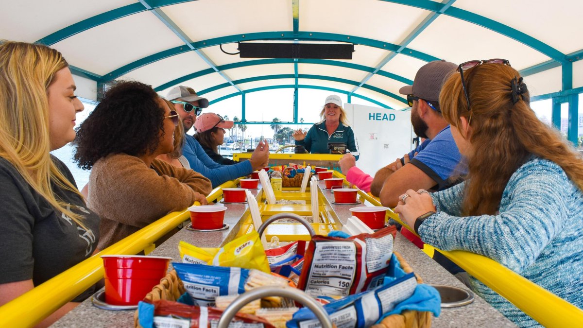 A group of friends enjoy food and drinks on a paddle boat tour.