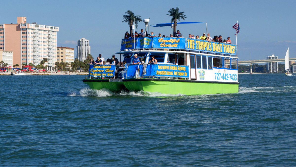 A tropical-themed tour boat cruises through the water during the day.