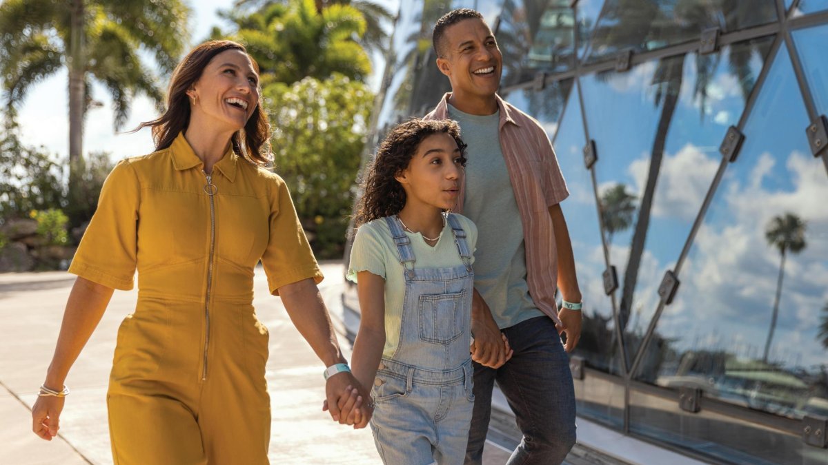 a mother and father hold hands with a little girl while walking outside the dali museum