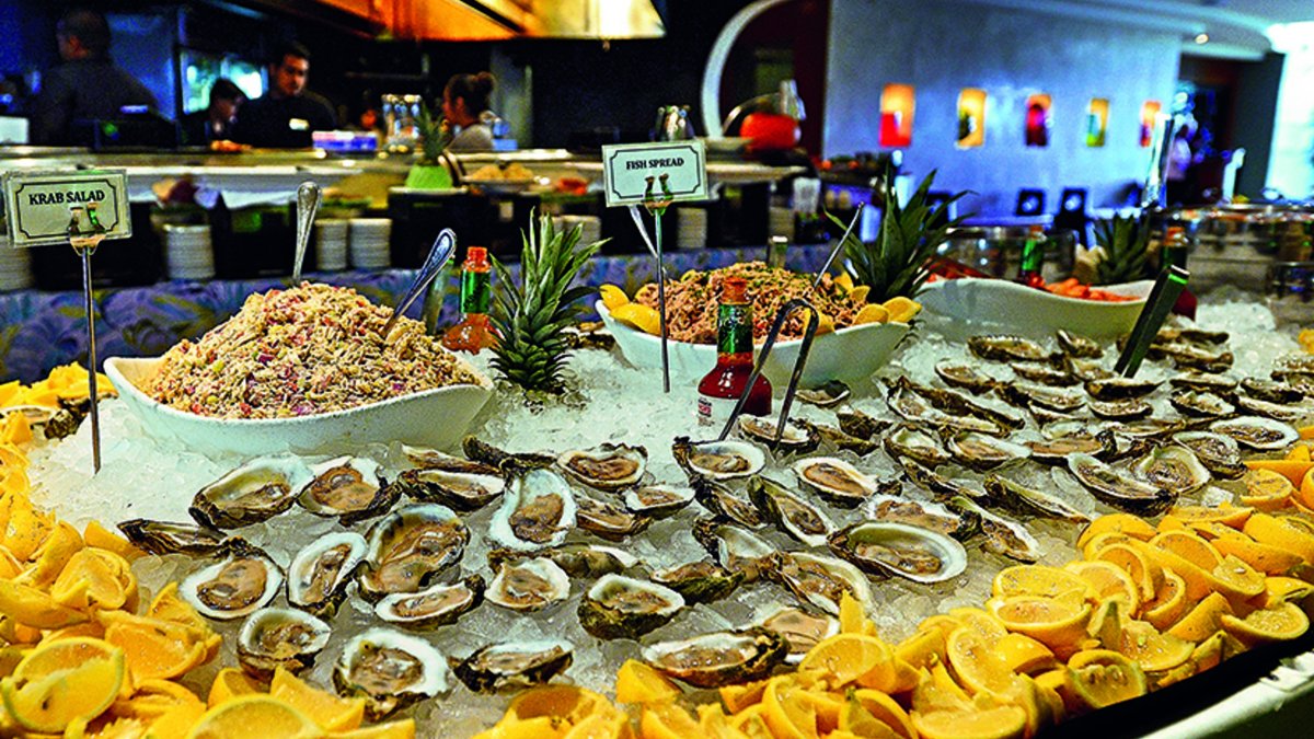 A buffet display of oysters, lemons and other salads over ice