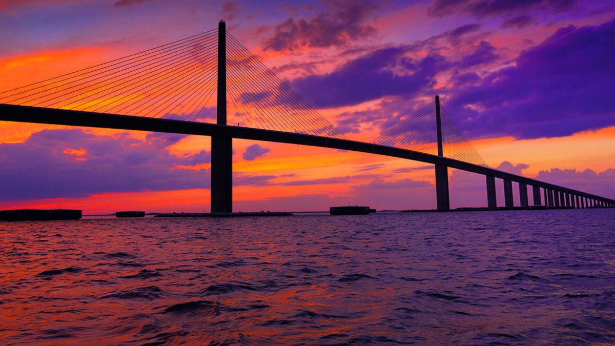 a gorgeous sunset in pinks and oranges behind the Sunshine Skyway Bridge in Tampa Bay