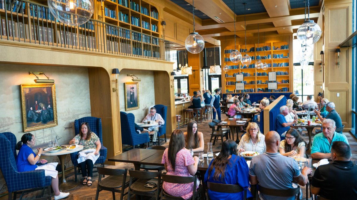 Diners enjoy a meal in a restaurant that looks like a library surrounded by shelves of books