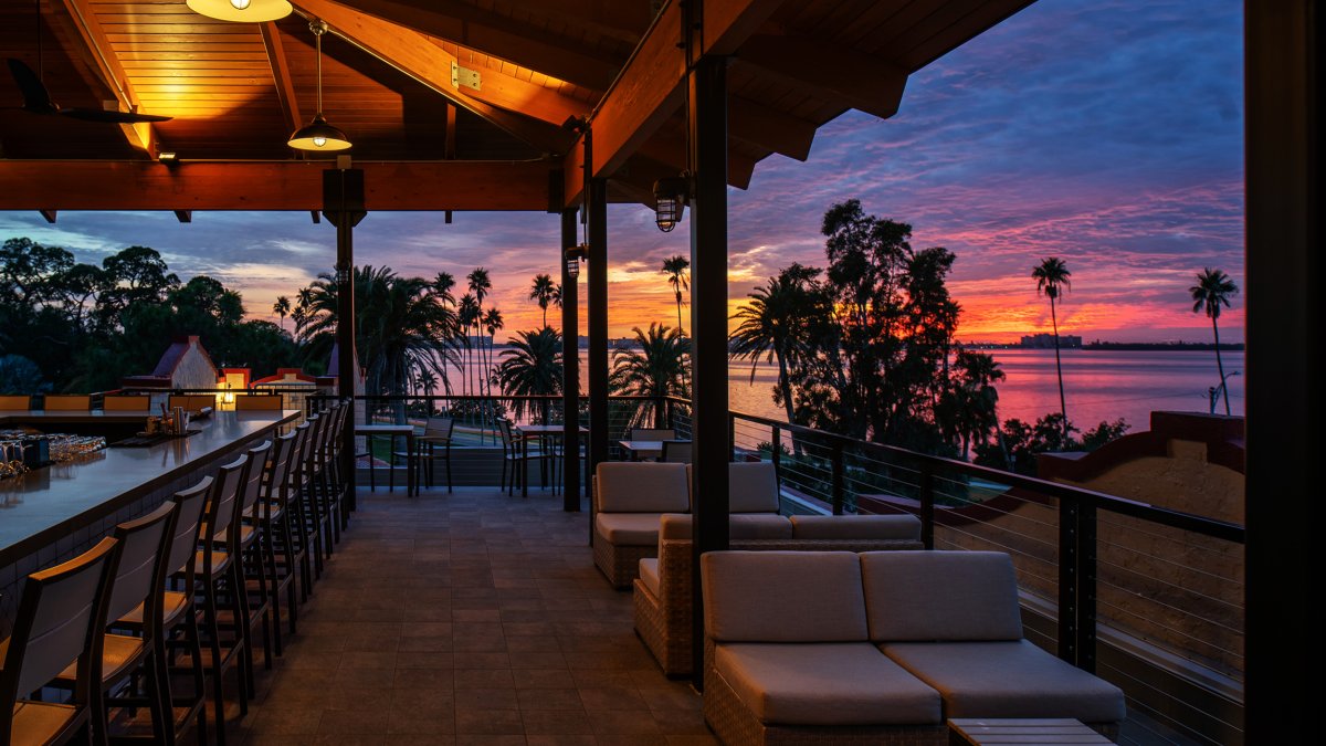 a beautiful rooftop deck and bar at sunset with a view of the water at the Fenway Hotel