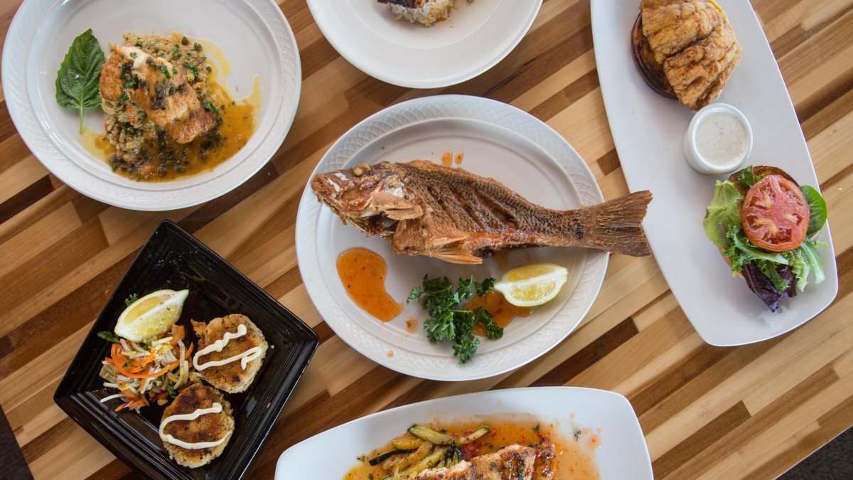a wooden table with a variety of seafood dishes on white plates and platters