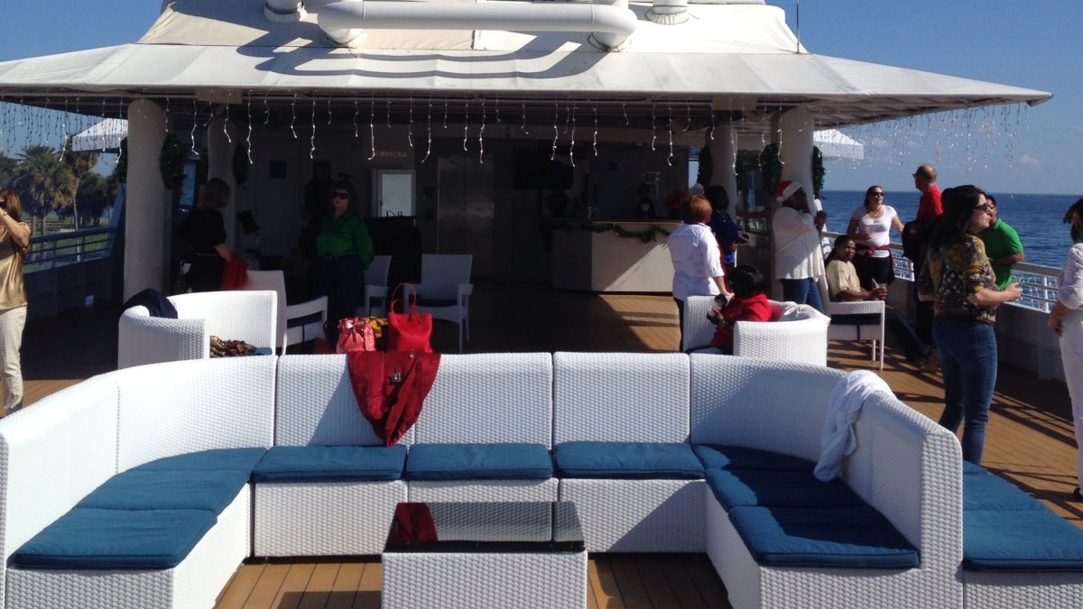 The top deck of a yacht with furniture and people looking at the ocean