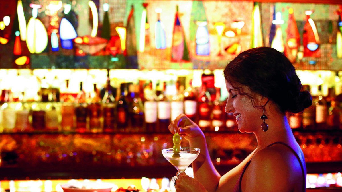 A woman sits at a bar with a cocktail