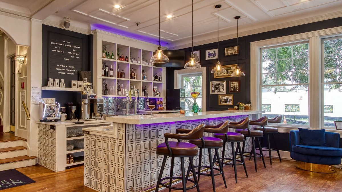 a stylish coffee bar with purple stools and a blue velvet chair inside a hotel