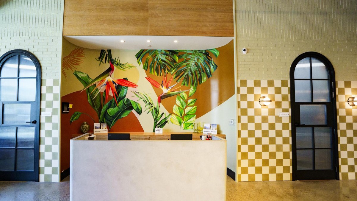 tropical mural behind a hotel front desk with gold checkerboard wallpaper in the background
