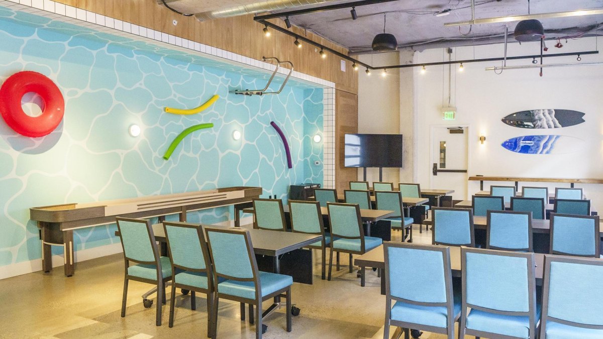 a meetings room with blue chairs and black tables with wall art that resembles a giant swimming pool with pool noodles and a swim ladder