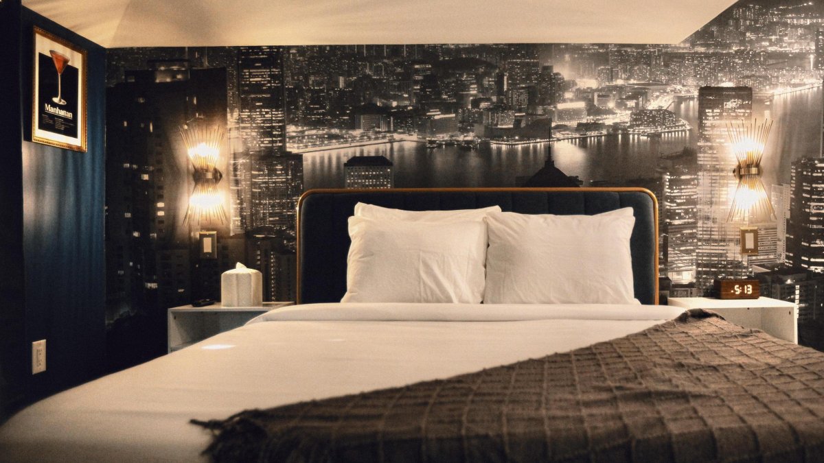 a hotel room decorated in black and white with a wall mural of a city behind it and wall art of a cocktail