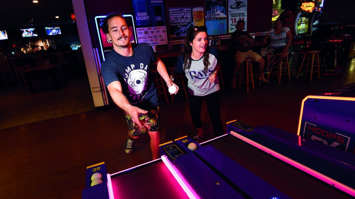 Two people playing skee ball in a bar