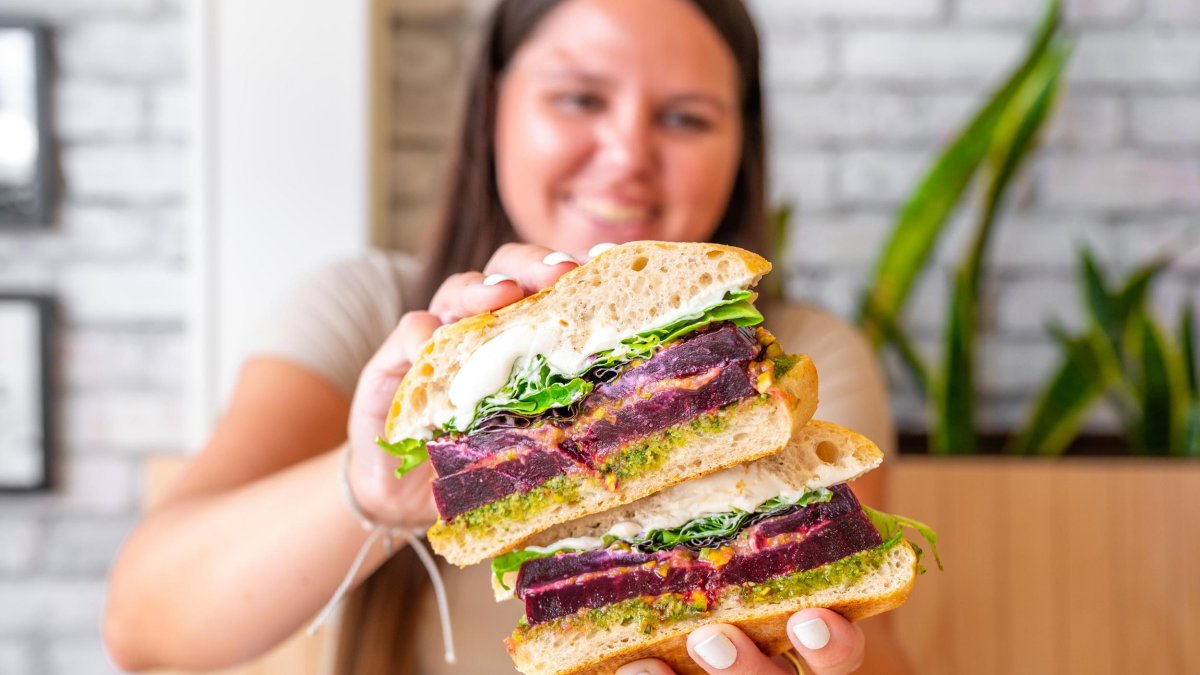 A woman holds up an open sandwich