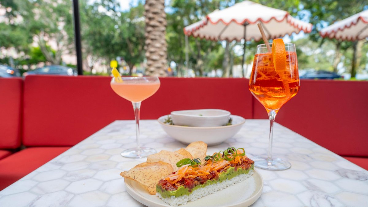 Two cocktails and a plate of food on a table at an outdoor restaurant