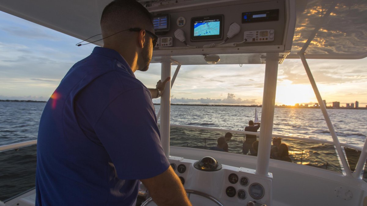 A boat captain steers along the water