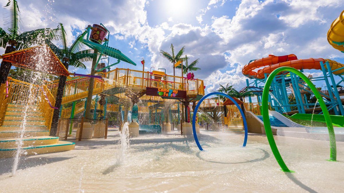 the colorful outdoor water play area with water slides, water shooting up out of the ground and stairs leading to more levels of interactive water fun. 