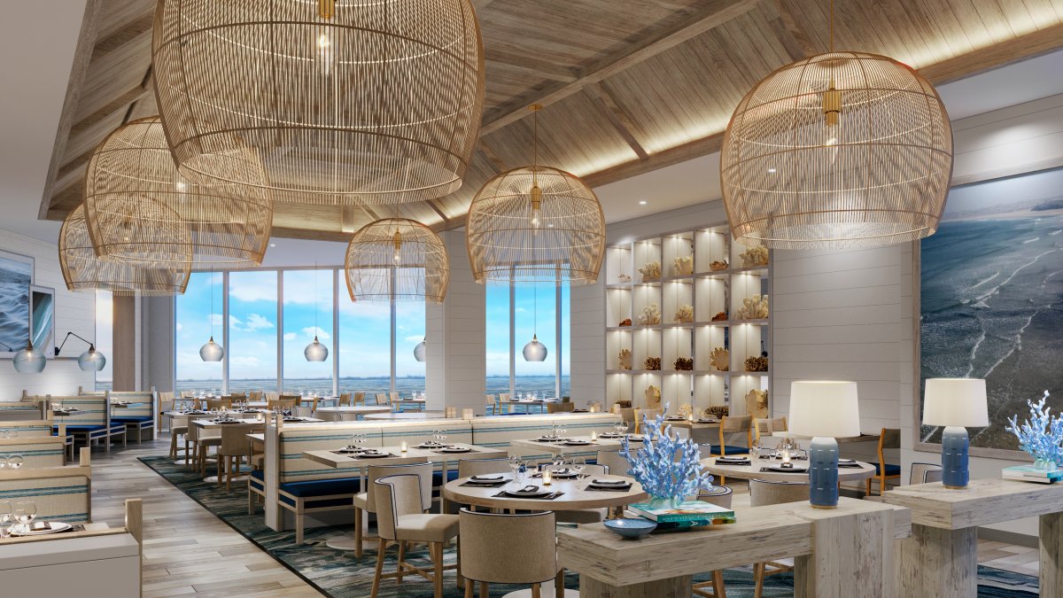 an elegant, empty hotel dining room with coastal decor and a view of the water