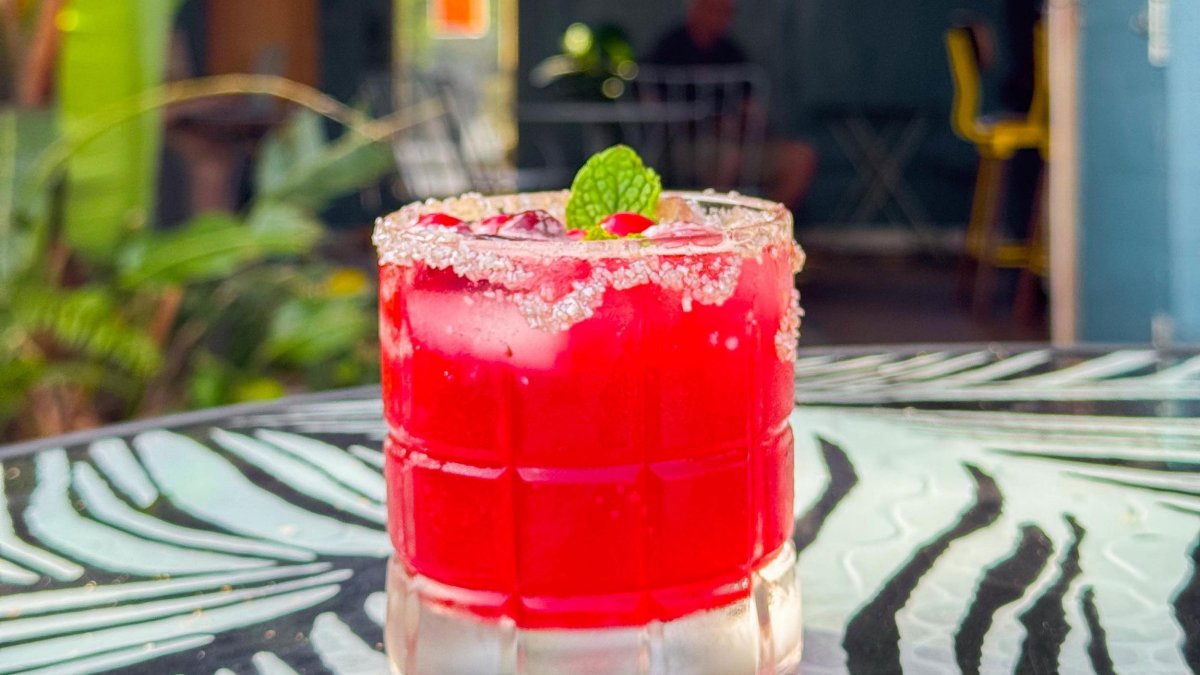 a bright red mocktail in a low glass with sugar on the rim and a mint leaf, set on a table decorated in a zebra style at Rabbit Rabbit smoothie and mocktail bar in St. Petersburg FL