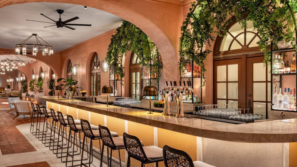 Veranda bar at the Vinoy Resort with empt barstools and large pink archways down a long hallway.