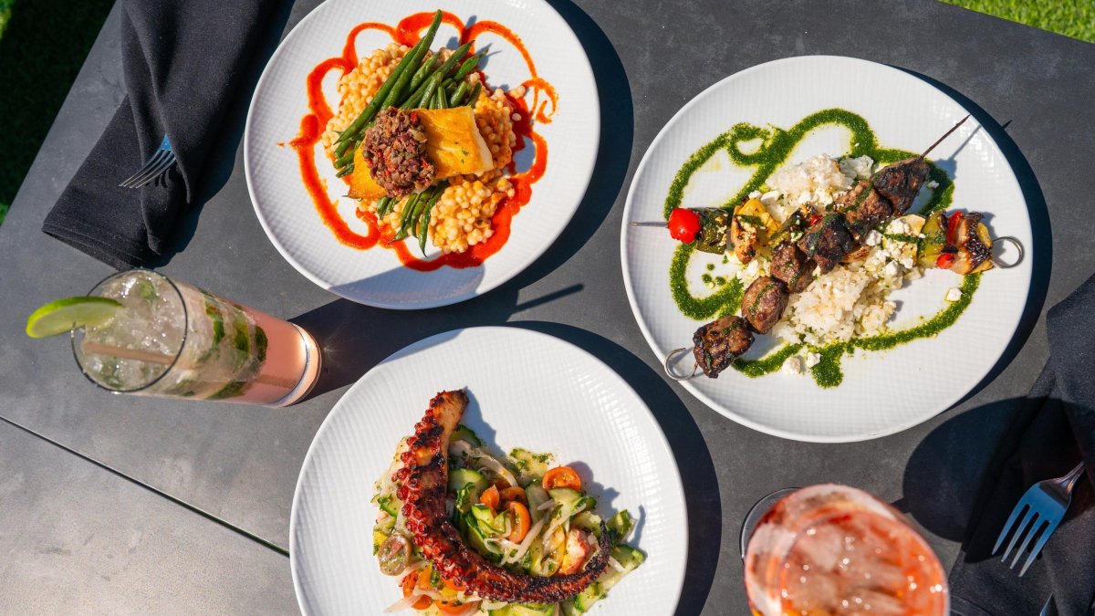 three artfully designed plates of food next to drinks on a table at Azura Coastal Kitchen