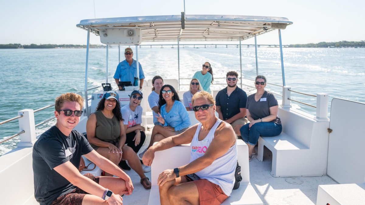 a group of people on a boat with mangrove islands in the background