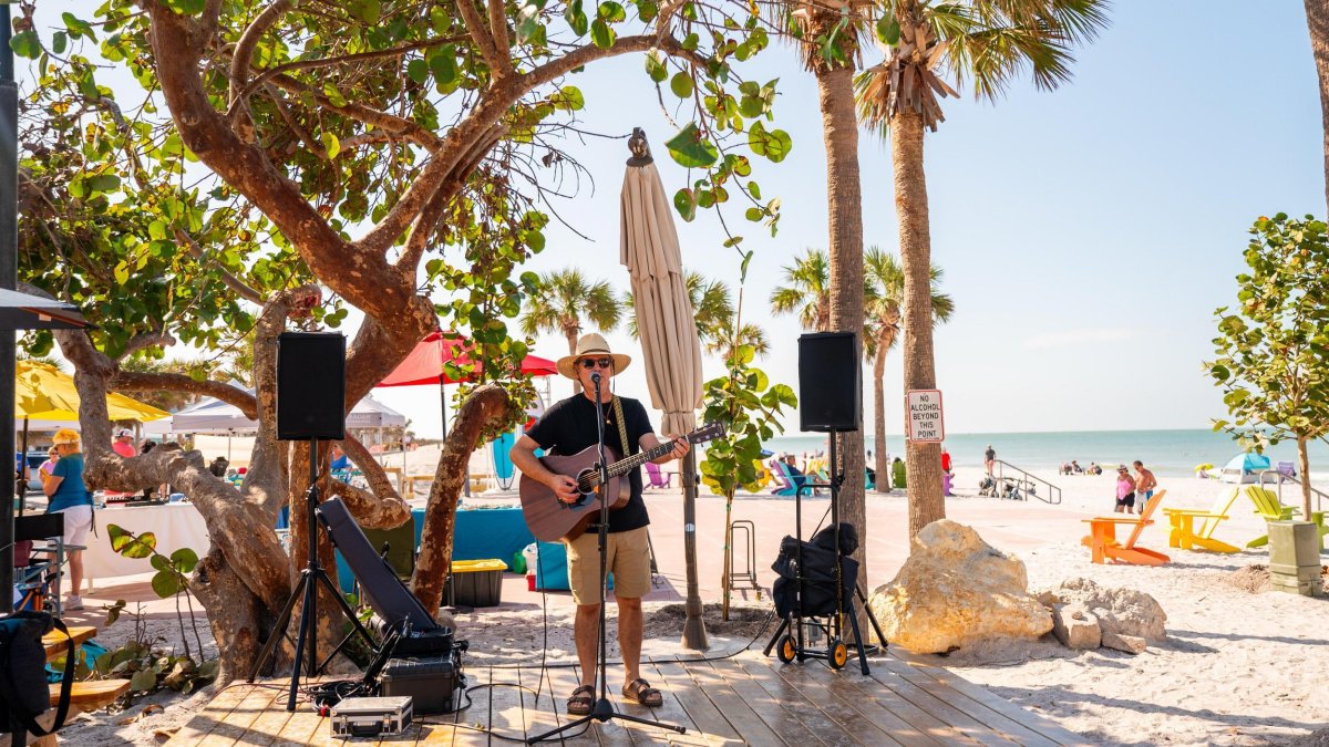 A musician plays guitar on the beach at Paradise Grille