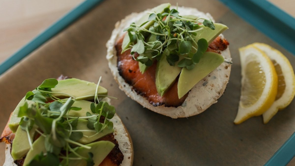 bagels and lox with avocado and bean sprouts on top