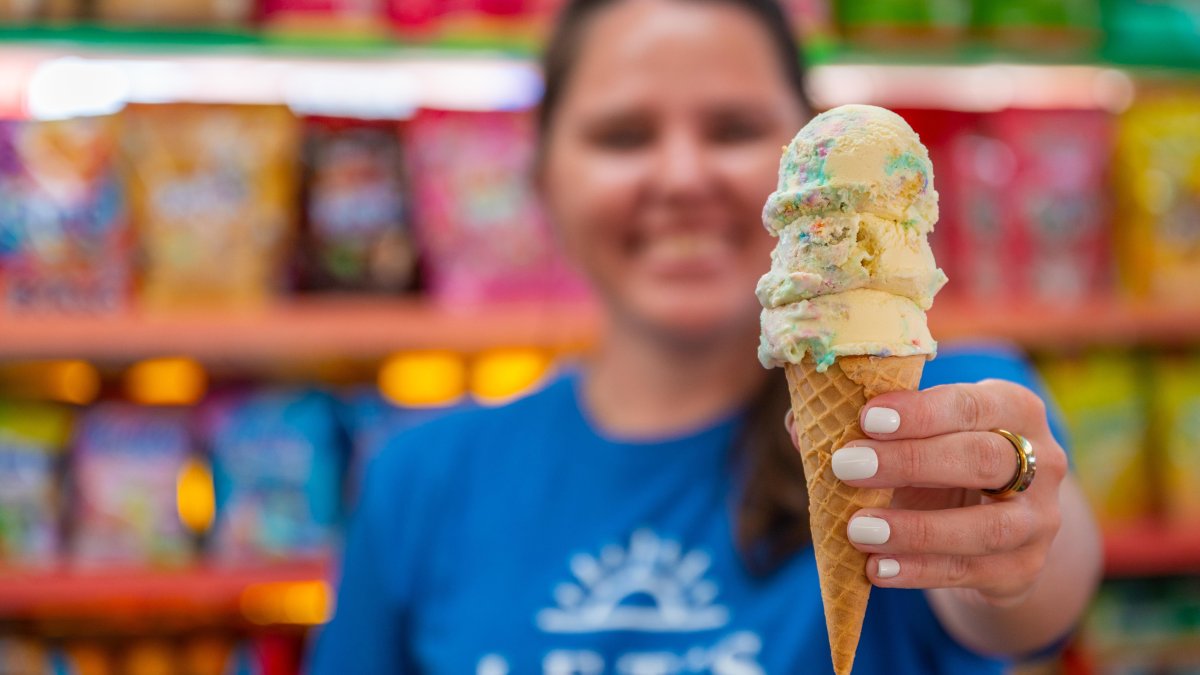 a person in a blue Tshirt holding out a stacked ice cream cone at Candy Kitchen