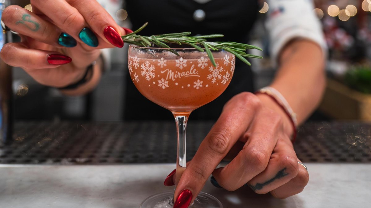 A bartender puts a garnish on a festive cocktail