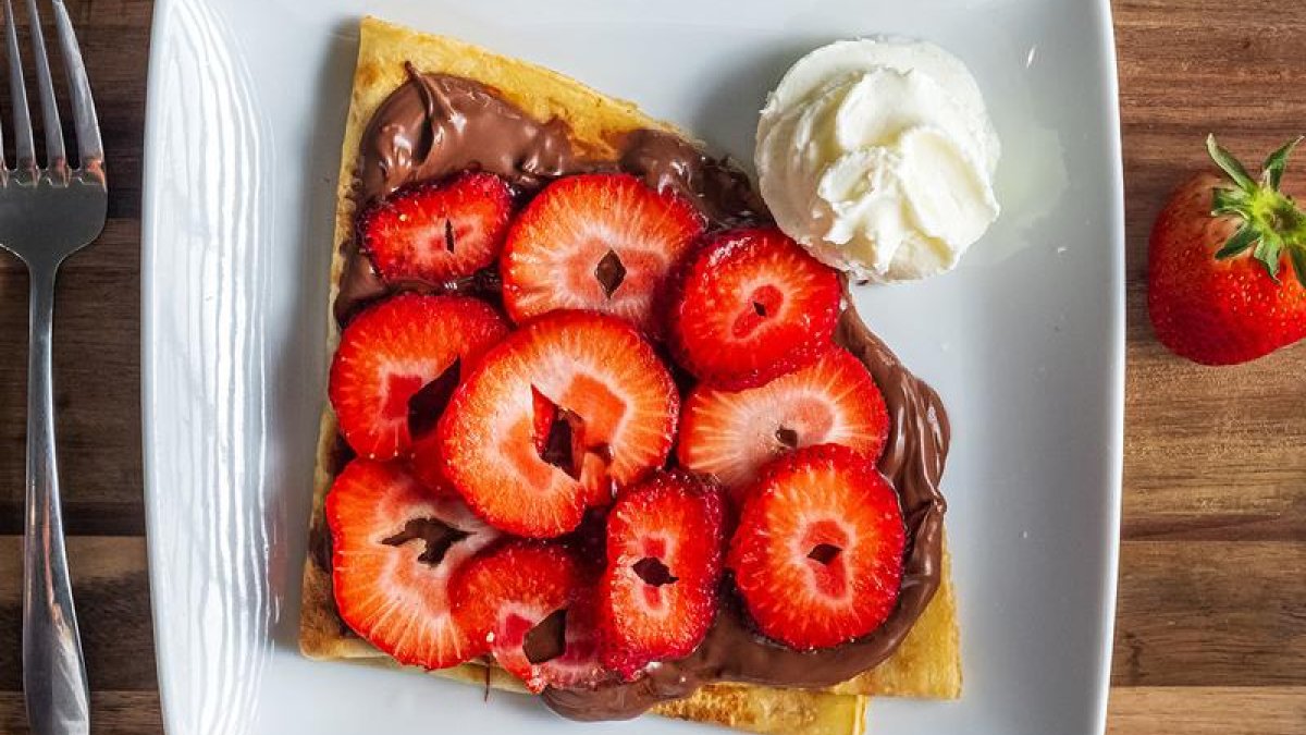 a crepe with nutella and strawberries on top with a dot of whipped cream at Copenhagen Cafe
