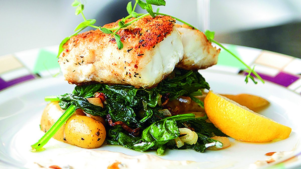 a seared piece of fish artfully perched on top of wilted greens and fingerling potatoes at Grace restaurant on St. Pete Beach