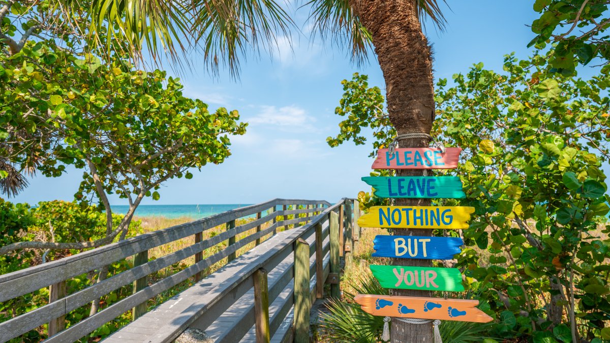 a sign encouraging beach visitors to leave only their footprints, placed near a boardwalk to Indian Rocks Beach