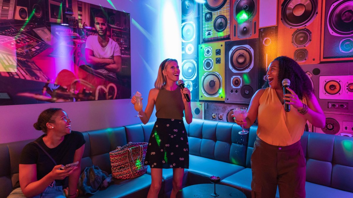 three women having fun in a neon-lit karaoke room at LALA St. Pete