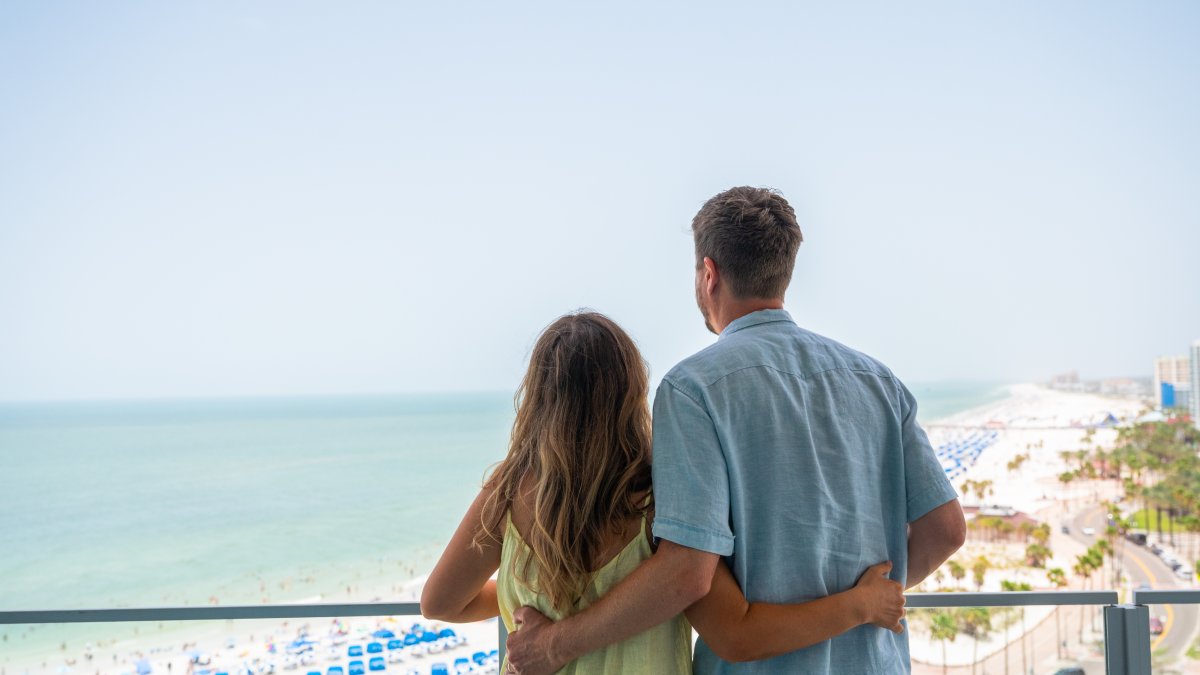 A couple looks out at the balcony of a beachfront resort
