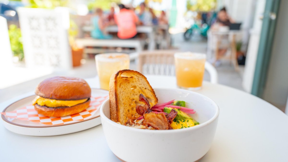 a breakfast bowl with hashbrowns, eggs, bacon and toast next to a breakfast bagel on an outdoor table at Grove Surf Cafe in Indian Rocks Beach